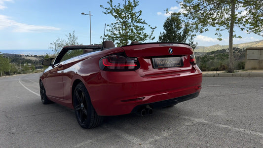 2020 Red BMW 2 Series Convertible back left side with roof down, pictured on street with trees in Spain