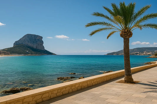 Sunny promenade in Calpe, Costa Blanca with palm trees, turquoise sea, and the Peñón de Ifach mountain in the distance — ideal road trip stop in Spain.