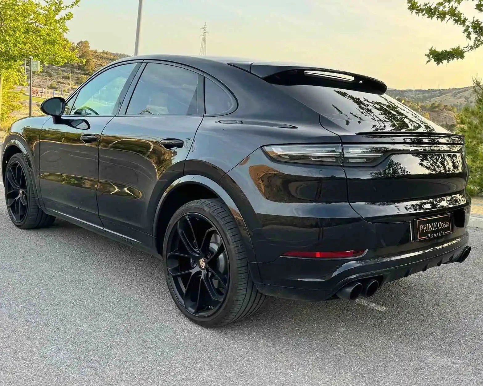 2020 Black Porsche Cayenne back left side pictured on street surrounded by trees, in Spain