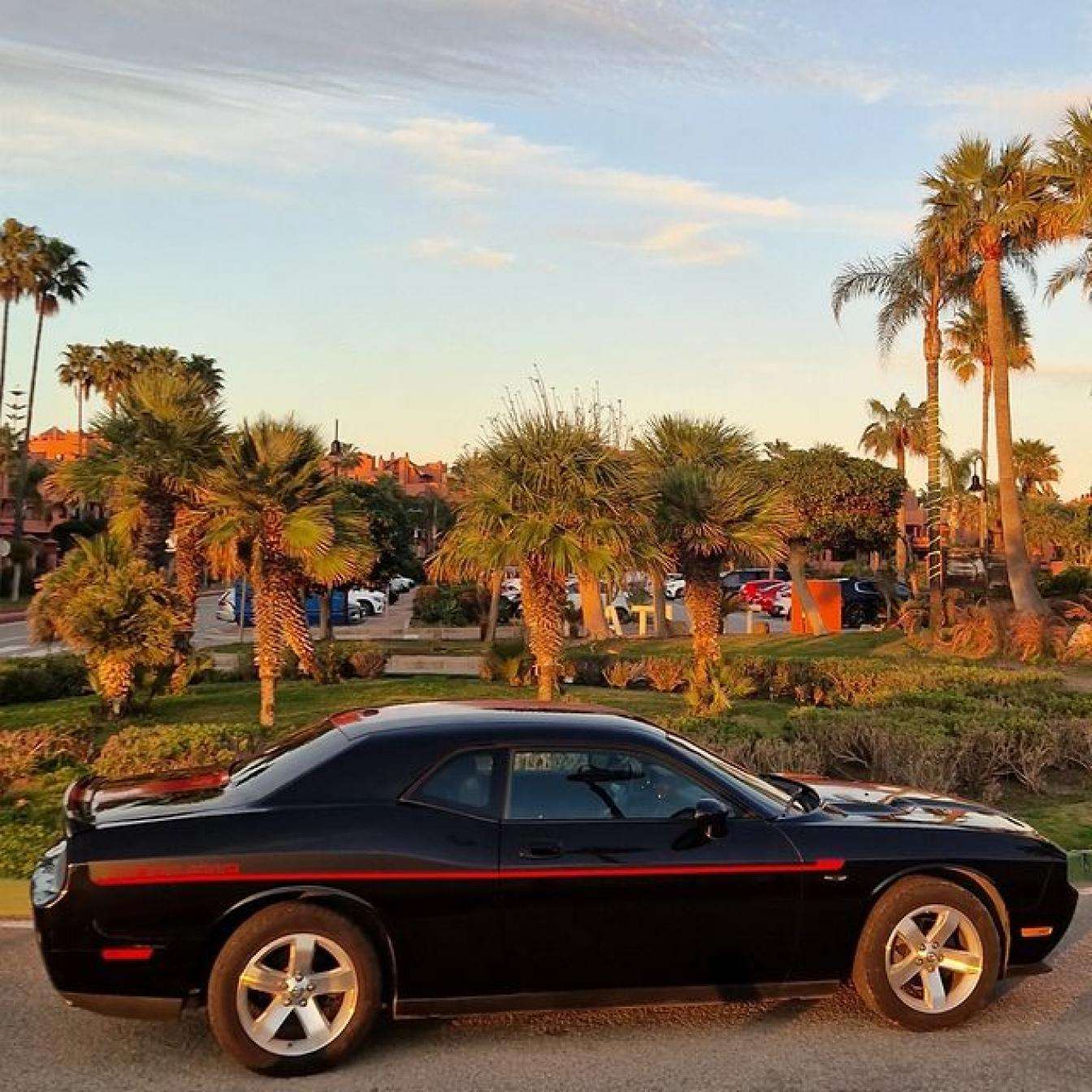 Black and red Dodge Challenger for rent in Marbella – automatic American muscle sedan.
