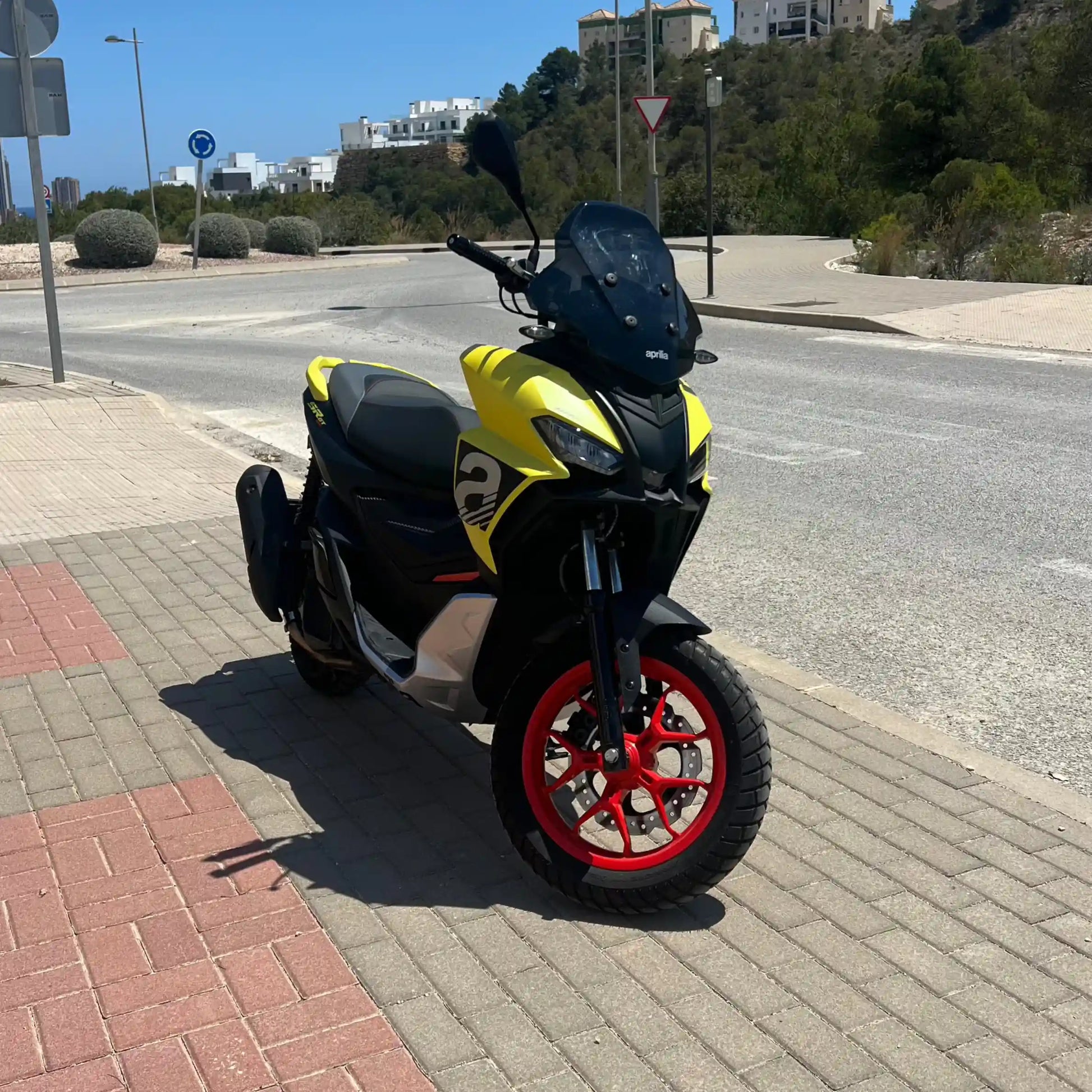 2025 Yellow Aprilia SR GT 125 scooter front pictures on side of empty street in Spain