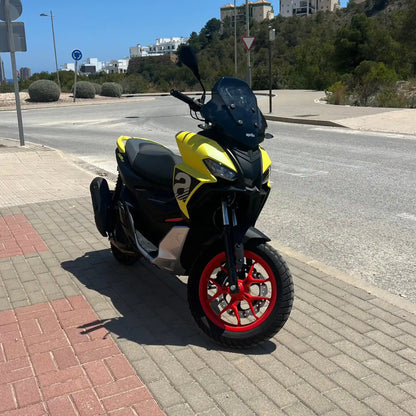 2025 Yellow Aprilia SR GT 125 scooter front pictures on side of empty street in Spain