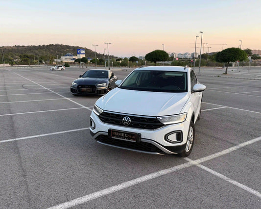 White 2024 Volkswagen T-Roc front left side in parking with grey Audi RS5