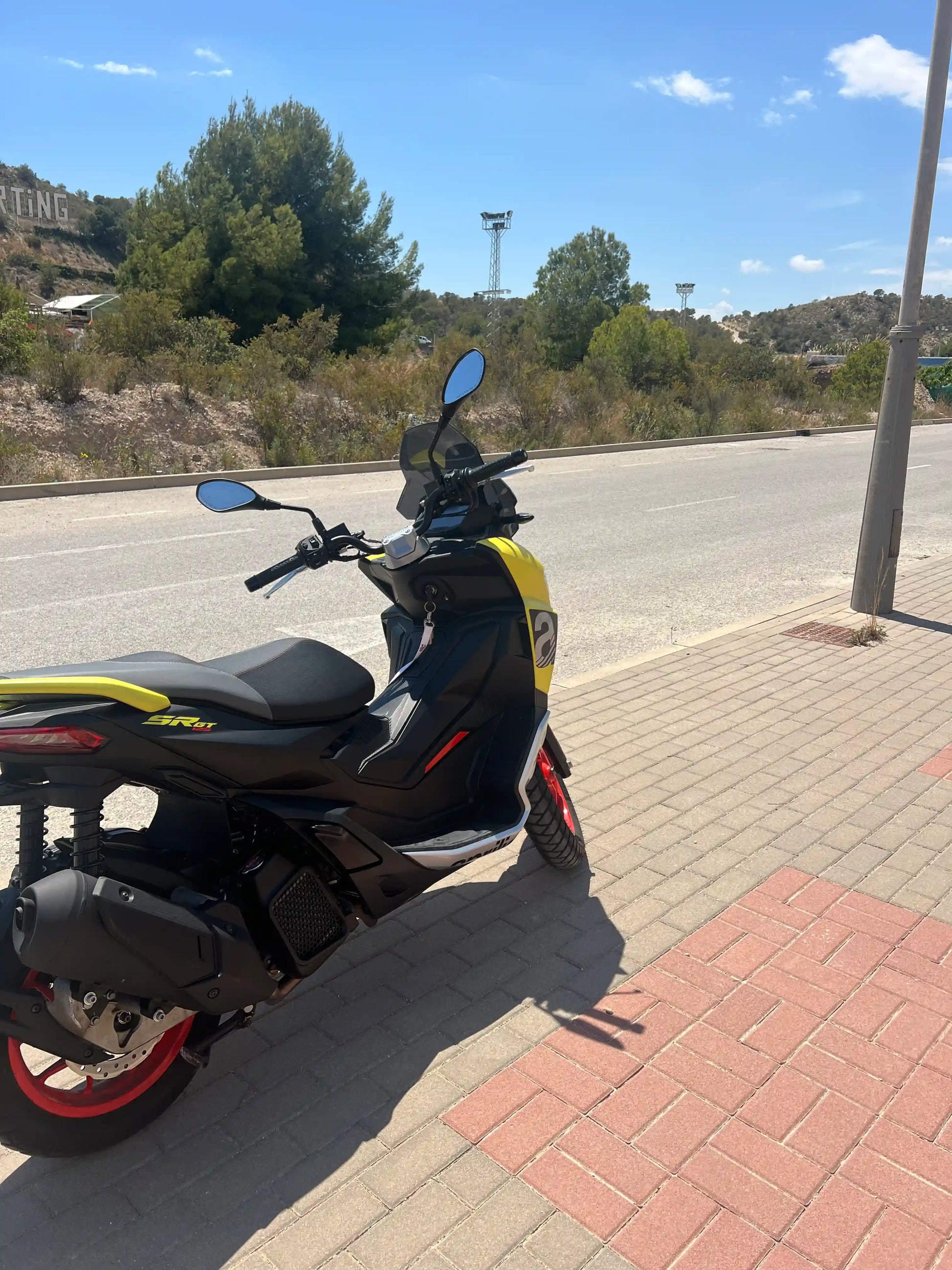 Yellow 2025 Aprilia SR GT 125 scooter from side on the street in Spain