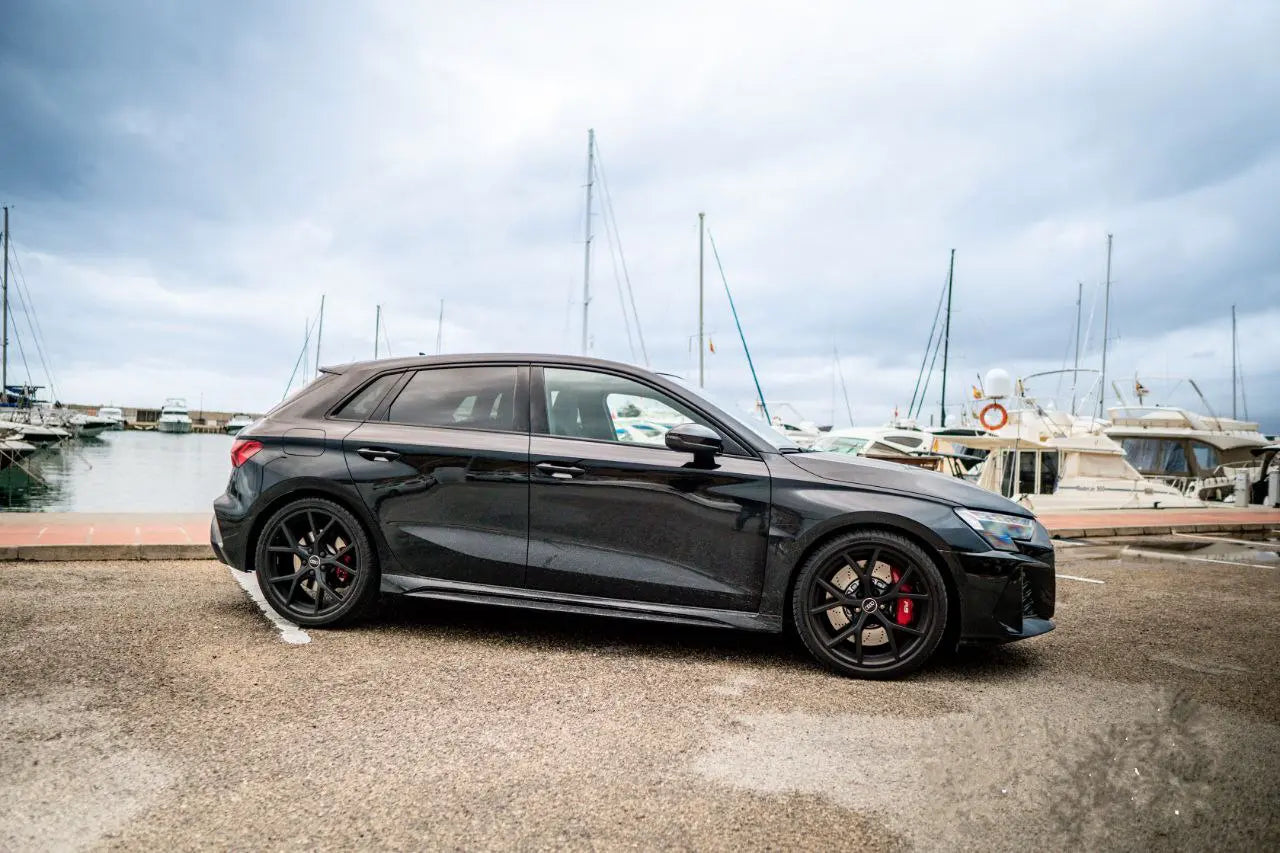 Black Audi RS3 right side pictures in parking near seat and ship port