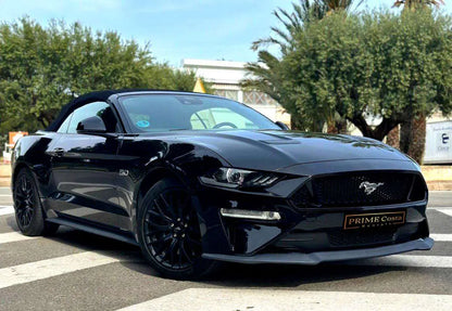 Black Ford Mustang GT 5.0 Convertible front right view in empty parking surrounded with trees