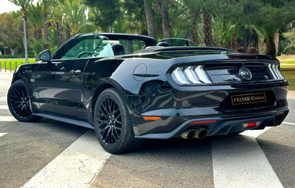 Black Ford Mustang Convertible back left corner in parking space with trees