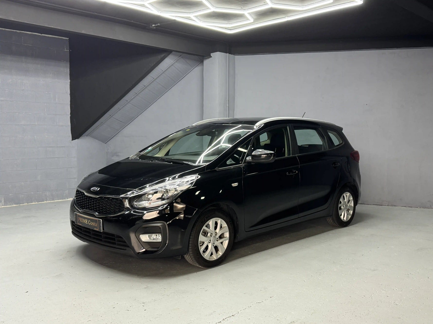 Black Kia car in a showroom with gray walls and floor.